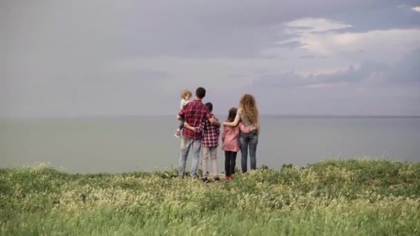 一个由5个人组成的大家庭- -一个女儿和两个儿子站在山上，望着多云的天空。儿童和母亲的概念。父母和孩子一起走. — 图库视频影像