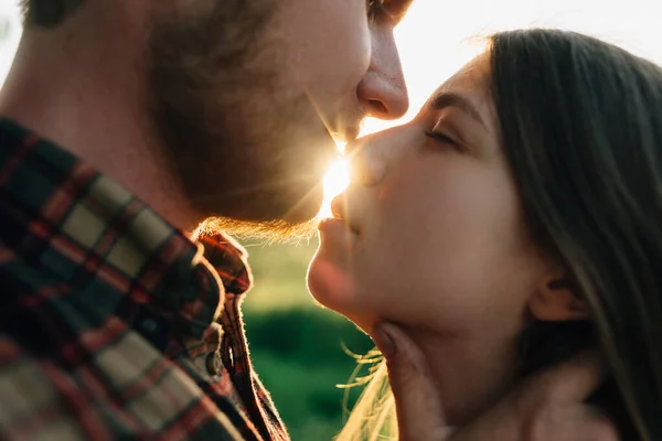 夕日の光で髭とブルネットの女の子と恋人のカップルのキスの肖像画。鼻の上で若い家族の夫と妻のキスのクローズアップ. — ストック写真