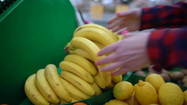 Close-up van vrouwelijke handen nemen bananen uit de vitrine in de supermarkt. Levensmiddeleninkoopconcept. — Stockvideo