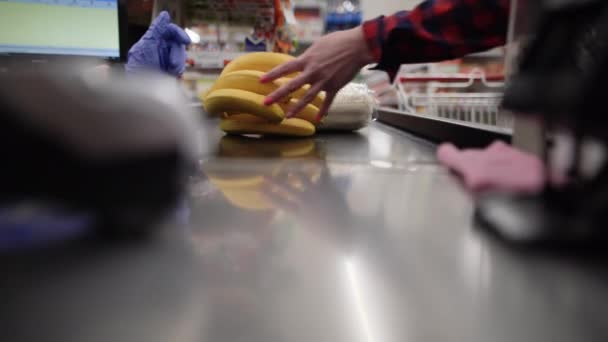 Gros plan d'un client plaçant des marchandises sur un tapis roulant au comptoir de caisse. Achat de fruits et légumes. — Video