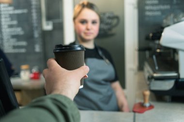 Bir kafede bir bardak sıcak espresso kahvesi ve elinde kahve bardağıyla müşterilerin yakın çekimleri. Bir kafeteryada veya barda tek kullanımlık sofra takımı.