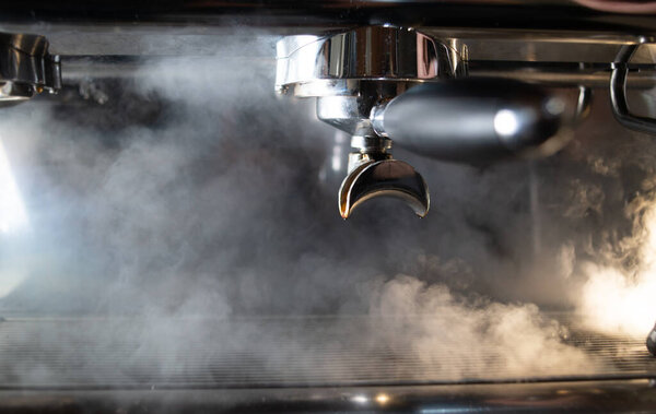 a lot of steam from the coffee machine. the coffee maker is smoking and steaming. steam treatment of a surface in a cafe.