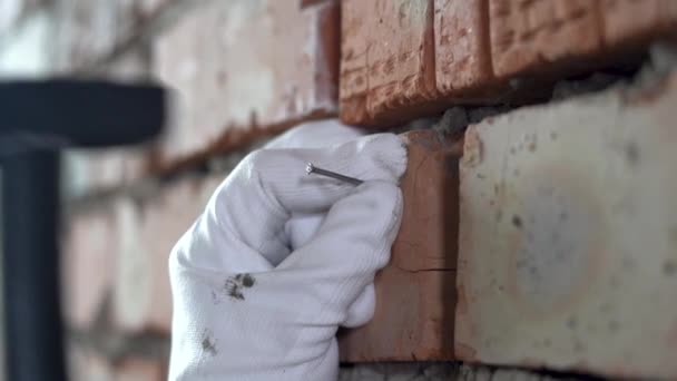 El primer plano de la mano clava el clavo en la pared de ladrillo. — Vídeos de Stock