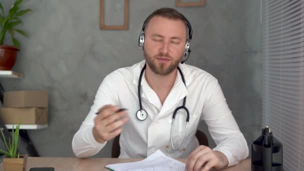 Médico caucasiano conversando com a câmera durante uma consulta de telemedicina, consultando um paciente em uma reunião de bate-papo virtual. Chamada de vídeo App, headshot. Vista Webcam. — Vídeo de Stock