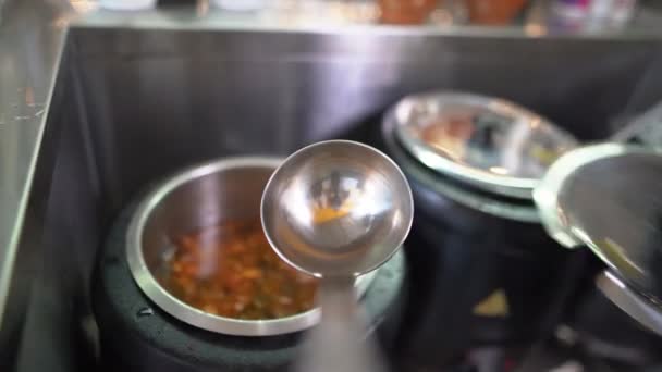 Primer plano en un buffet en la línea de distribución de alimentos, una sopa roja caliente, aromática y deliciosa con carne de res y aceitunas se recoge en un cucharón grande. — Vídeos de Stock