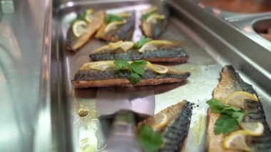 Pişmiş lezzetli uskumru balığı büfedeki ya da yemek odasındaki yiyecek dağıtım hattında büyük bir mutfak spatulasına yerleştirilir..