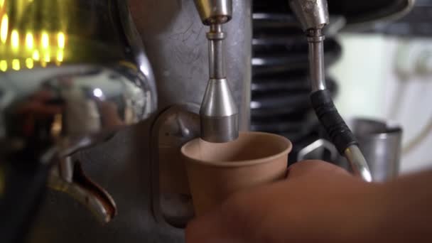 Heißes Wasser aus der Kaffeemaschine wird in Kaffeepausen oder Kaffeepausen in eine Americano-Einwegbecher gegossen. Nahaufnahme. — Stockvideo