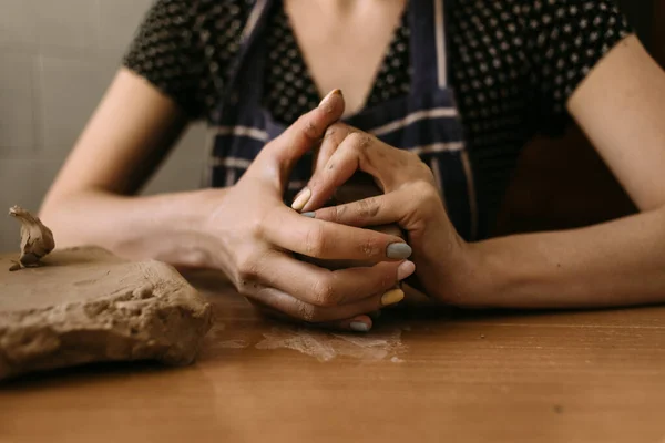 Gros plan Les mains d'une sculptrice pétrissent de l'argile sur la table à la maison. hobby modélisation de l'argile. — Photo