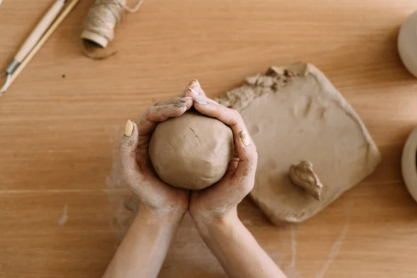 Potter works with clay, close-up top view female hands hold a piece of wet clay in their hands. The potter creates a product. — Stock Photo, Image