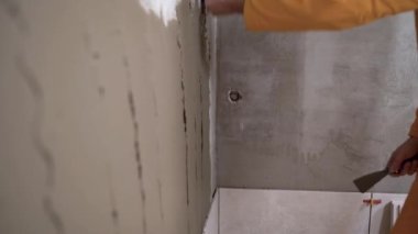 Banyo kiremitlerine seramik serpiştirmek için yapışkan karışım. Duvara spatula ya da mala sürerek. Fayansların döşenmesi için yüzey hazırlanıyor. Ev yenileme konsepti.
