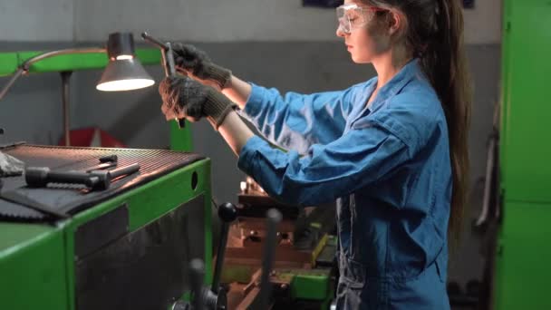 En kvinnlig mekaniker bearbetar ståldelar i en produktionsverkstad. Begreppet industriarbetare i en fabrik. — Stockvideo