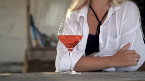 Primer plano de cóctel naranja en un bar, en un bar al aire libre cerca del océano, una mujer toma una bebida refrescante y lo bebe. — Vídeos de Stock