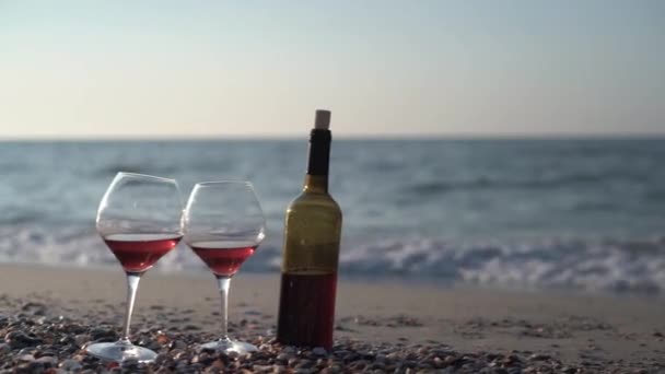 Romantico picnic con bicchieri di vino rosso rosato sulla spiaggia in una giornata estiva soleggiata. Il mare è sullo sfondo. — Video Stock