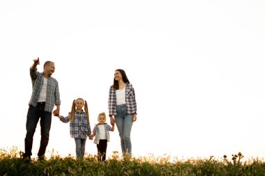 Mutlu aile babası, anne ve kızları yazın gün batımında doğada yürürler. Çocuklu ebeveynler hafta sonları birlikte vakit geçirirler. Mutlu aile ve çocukluk kavramı.