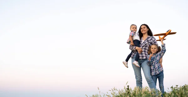 Mothers day happy family mom and her loving daughters mother walking on a weekend summer evening stand looking at the sky and place for text. Two girls with smiling woman. Motherhood concept.