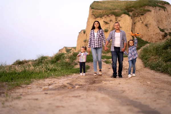 Happy family walks on nature mother father and daughters for a walk go along the road near the cliff. Weekend or summer vacation time together for parents and children. childhood concept.