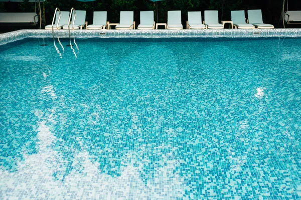 Prázdný bazén s modrými mozaikovými dlaždicemi bez lidí. Místo pro letní dovolenou a odpočinek. Lehátka u bazénu v hotelu. Koncept hotelového koupaliště — Stock fotografie