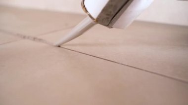 Kapalı bir silahla silikon dolgu macunu sürerken yakın plan görüntü, banyodaki seramik fayanslara silikon yapıştırıcı. Servis kavramı.