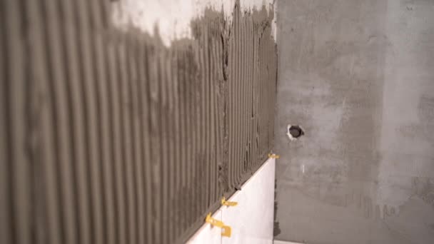 Tegels op de muur leggen. specialist legt keramische tegels, klemmen en aanpassen, het installeren van plastic industriële kruisen voor bevestiging. Huisrenovatieconcept. — Stockvideo