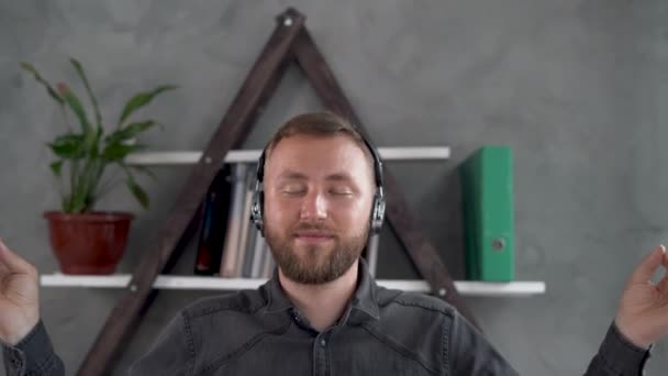 Caucasian bearded man sits in the office with closed eyes and meditates in the lotus position while working. Crumpled sheets of paper are scattered on the table. Calmness and unity with yourself — Stock Video