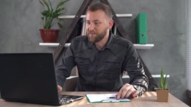 Beyaz sakallı bir adam evinde, masada oturuyor dizüstü bilgisayara bakıyor ve başvuru formu üzerinden video görüşmesi yapıyor. Müşterilerle uzak mesafeden iletişim.