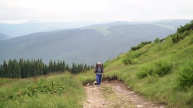 Büyük bir turist sırt çantalı beyaz bir erkek turist dağ yolundan tırmanıyor..