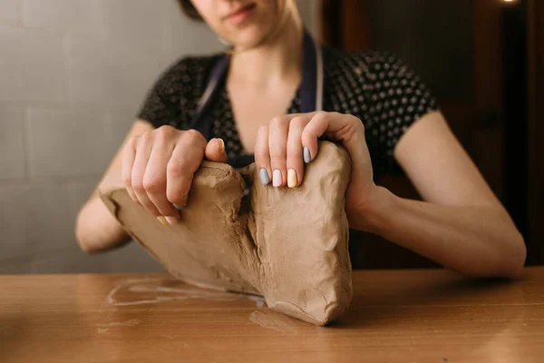 Zbliżenie żeńskich rąk garncarza, zaczyna robić produkt z gliny, bierze duży kawałek materiału i dzieli go na dwie części. — Zdjęcie stockowe
