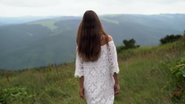 Visszapillantás egy nő turista fehér ruhában sétál végig a hegygerincen, és élvezi a gyönyörű természeti táj. — Stock videók