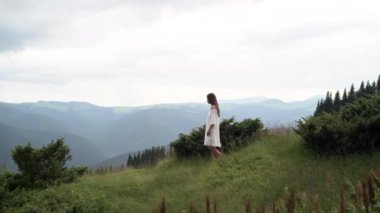 Beyaz bir elbise giymiş güzel beyaz bir kadın yamaçta yalınayak yürüyor..