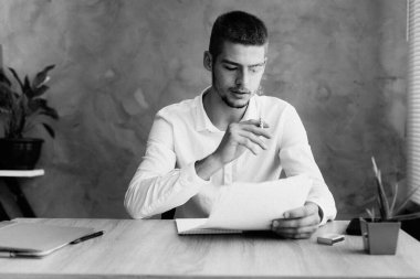 Serious smoking guy with a cigarette sitting in the office solves the problems of the corporate bankruptcy crisis. Businessman works signing a contract registration. business crisis concept High photo