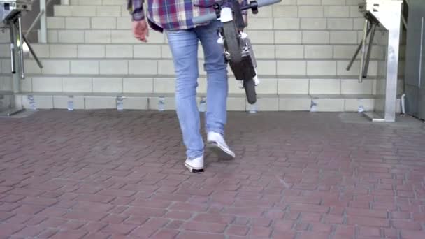Großaufnahme eines Mannes, der einen Elektroroller die Treppe hinauf trägt. Ohne Gesicht. Elektronische Mobilität. Ökologischer Stadtverkehr. — Stockvideo