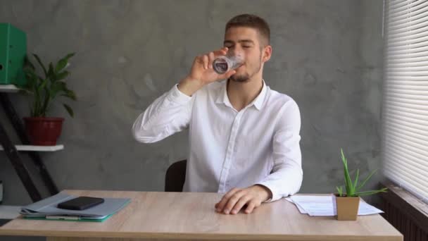 Portrait of a serious man drinking pure mineral water from a glass in the office. businessman drinks clean water. dehydration. health concept. — Video Stock