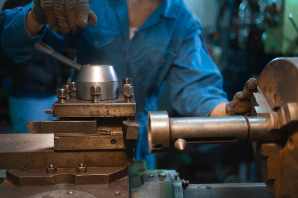 close-up of the hands of the master rotate the handle on the lathe.