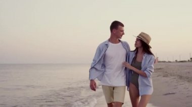 Mutlu evli çift ya da aşıklar okyanus ya da deniz kıyısında yürür birbirlerine sarılır ve sahilde tutkuyla öpüşürler. Tropik tatil beldesinde tatil kavramı.