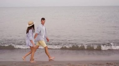 Genç ve güzel bir çift deniz ya da okyanus boyunca yürüyorlar. Gömlek giymiş bir adam ve bir kadın, el ele tutuşuyorlar ve güzel bir sohbet ediyorlar. Tatil köyünde aile tatili.
