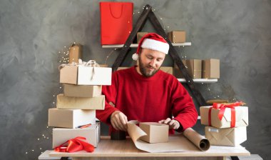 İş kurma KOBİ kavramı genç erkek girişimci, küçük işletme sahibi, eşya paketleme, sevkiyata hazırlık. Noel Baba şapkası giymek Noel sezonunda iyi bir gelir sağlar.
