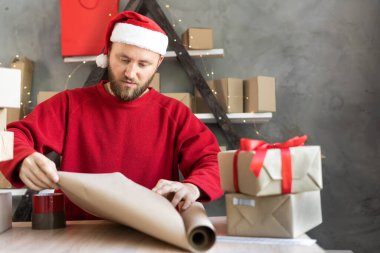 İş kurma KOBİ kavramı. Girişimci olmak isteyen genç bir erkek, küçük bir işletme sahibi, malları paketliyor, sevkiyata hazırlanıyor. Noel Baba şapkası giymek Noel sezonunda iyi bir gelir sağlar.