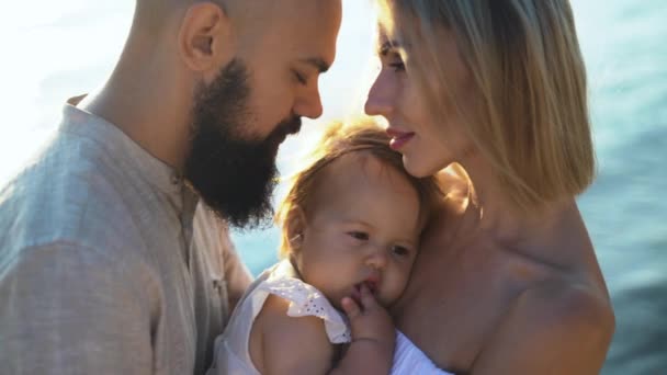 Portrait of a young married couple and their cute daughter having fun on the beach at sunrise. — Stock Video