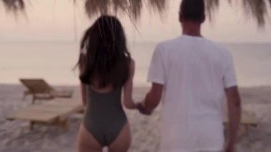 Çiftler gün doğumunda tropikal bir plajda koşu yaparken yaz tatilinin tadını çıkarıyorlar. Sevgi dolu genç bir çiftin yaz portresi. Tropik bir ülkede tatil seyahati.