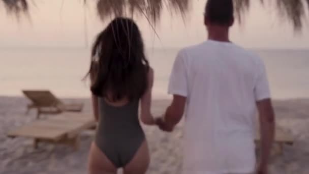 Pareja corriendo divertida en una playa tropical al amanecer disfrutando de vacaciones de verano. Retrato de estilo de vida de verano de pareja amorosa bastante joven. Viajes de vacaciones en un país tropical. — Vídeos de Stock