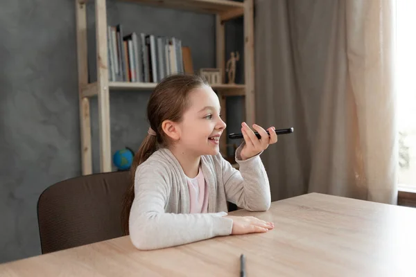 Voice assistant. Happy girl dictates text using microphone of smartphone or mobile phone. student on the phone records an audio message. Voice sms recording.copy space