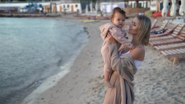 Beautiful young mother is having fun with her cute daughter on the beach in autumn or spring. — Stock Video