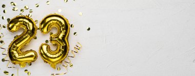 Altın folyo balonu 23 numara. 23. yazılı doğum günü ya da yıldönümü kartı. Gri beton arka plan. Yıldönümü kutlaması. Pankart. Boşluğu kopyala