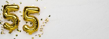 55 numaralı altın folyo balonu. Üzerinde 55 yazan doğum günü ya da yıldönümü kartı gri beton arka plan. Yıldönümü kutlaması. Pankart. Boşluğu kopyala
