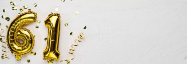 Altmış bir numaralı altın folyo balonu. Doğum günü ya da yıldönümü kartı. Altında 61 yazan gri beton arka plan. Yıldönümü kutlaması. Pankart. Boşluğu kopyala
