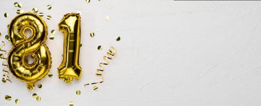 Seksen bir numaralı altın folyo balonu. Doğum günü veya yıldönümü kartında 81 yazılıydı. Gri beton arka plan..