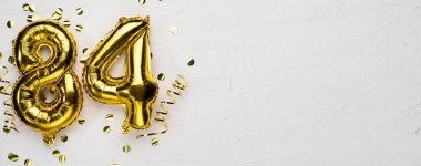 84 numaralı altın folyo balonu. Doğum günü ya da yıldönümü kartında 84 yazılıydı gri beton arka plan. Yıldönümü kutlaması. Pankart. Boşluğu kopyala