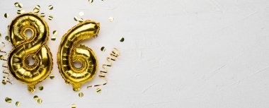 86 numaralı altın folyo balonu. Doğum günü ya da yıldönümü kartında 86 yazılıydı. Gri beton arka plan. Yıldönümü kutlaması. Pankart. Boşluğu kopyala