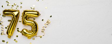 75 numaralı altın folyo balonu. Doğum günü ya da yıldönümü kartı, üzerinde 75 yazılı gri beton arka plan. Yıldönümü kutlaması. Pankart. Boşluğu kopyala