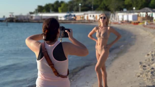 Séance photo sur la plage. Modèle femme professionnelle sur la plage en maillot de bain posant pour un photographe. — Video